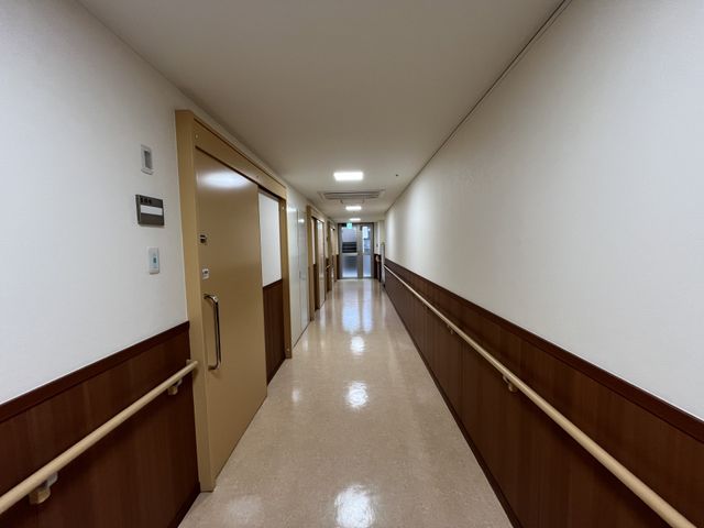 手すりのある廊下 廊下 手すりが設置されており、安全に配慮された歩きやすい通路です。長い直線が広々とした印象を与えます。