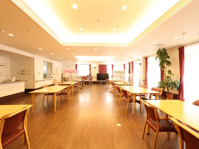 温かみのある共有ダイニング リビングダイニング 木のテーブルとイスが配置され、日の光が降り注ぐダイニングルームです。ゆったりとした時間を過ごせる空間で、日々の食事や交流が楽しめます。