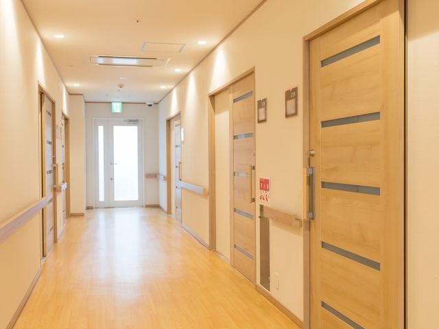 廊下の明るい様子 廊下 床が明るい木目調で統一された、清潔感あふれる廊下です。広々としており、ゆったりと歩ける空間が確保されています。