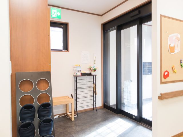 入口とフラワースタンド 玄関 ほっと一息つけるエントランスには、季節の花が彩りを添え、訪れる人をやさしく迎えてくれます。靴を整理できるスペースもあり、清潔感が保たれています。