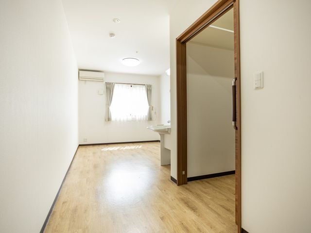 明るい居室の一角 居室   木目の床と白壁で、すっきりとした印象の居室です。窓から自然光が入り、明るい空間になっています。