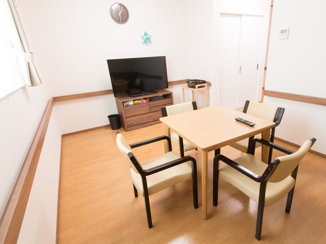 居室内のテーブルとテレビ リビングルーム シンプルで清潔感があり、テレビを見ながらゆったり過ごせる居室です。木目調の家具が温かみのある空間を演出しております。