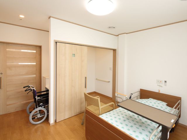 清潔な居室と車椅子 居室 落ち着いた色合いの居室は、必要な設備が整い、快適にお過ごしいただける空間です。車椅子もスムーズに移動できる造りになっております。