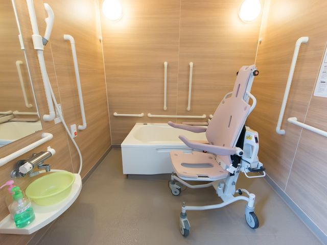 バリアフリーの浴室設備 浴室 手すりや移乗用いすを備え、安全かつ快適に利用できる洗い場です。清潔感があり、心地よいバスタイムをサポートします。