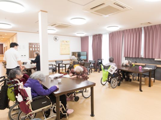 テーブルセットがたくさん置かれたフロアがある。入居者様が席について、テレビを観たり、お茶を飲んだりしている。