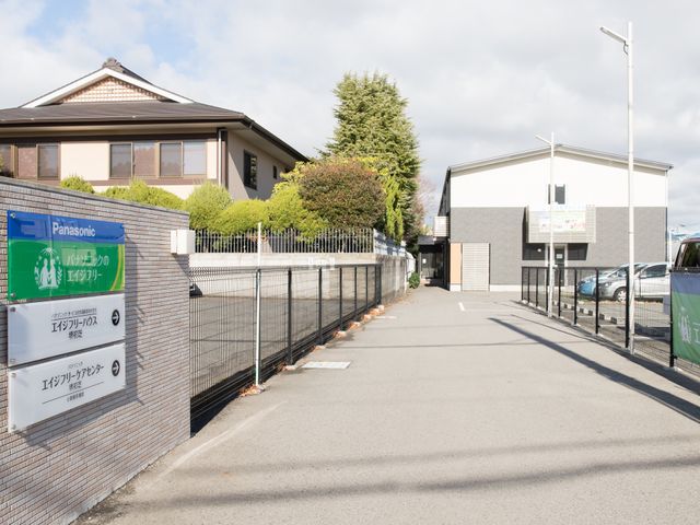 入口と外観の施設 看板 ゆとりのあるエントランスが印象的な施設外観です。きれいに手入れされた庭と落ち着いた色合いが、訪れる人の心を和ませてくれます。