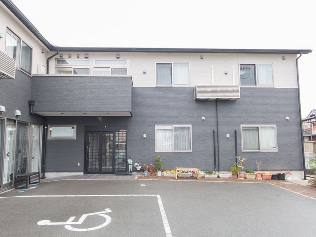 清潔感ある建物の外観 外観 ゆったりとした駐車スペースが確保された清潔な建物です。入口には手すりも設置され、安全に配慮されています。