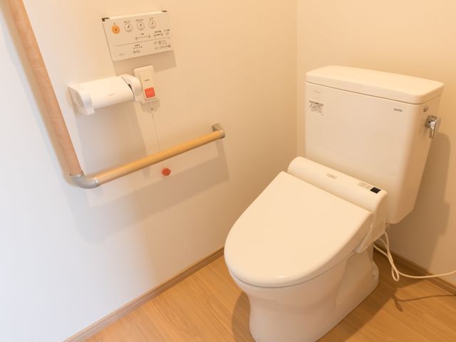 バリアフリーのトイレ設備 トイレ 手すり付きの清潔なトイレは、安全で快適な利用をお手伝いします。利便性と安心を提供する設計です。