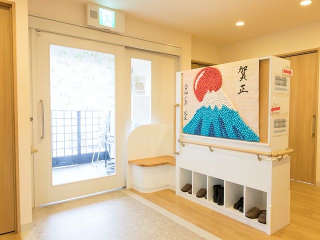 明るいエントランスと飾り 玄関ホール 手すりやベンチが配された快適なエントランスです。毎日の出入りが安全かつ心地良い環境が整っています。