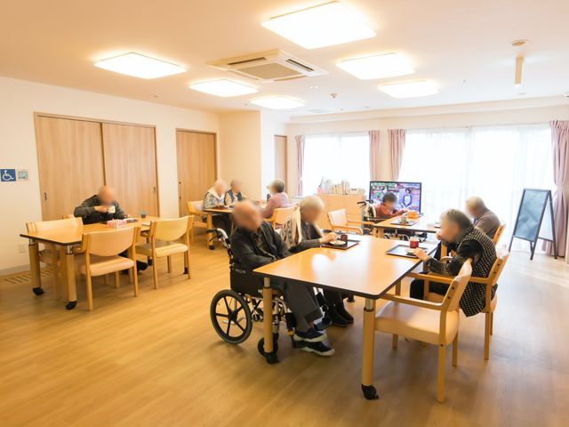 明るい食堂の様子 食堂 広々とした食堂で、来訪者が食事や憩いの時間を楽しんでおり、各テーブルはゆったりと配置されています。利用者同士が交流できるよう、明るく開放的な空間作りが行われており、働く環境としても快適そうです。