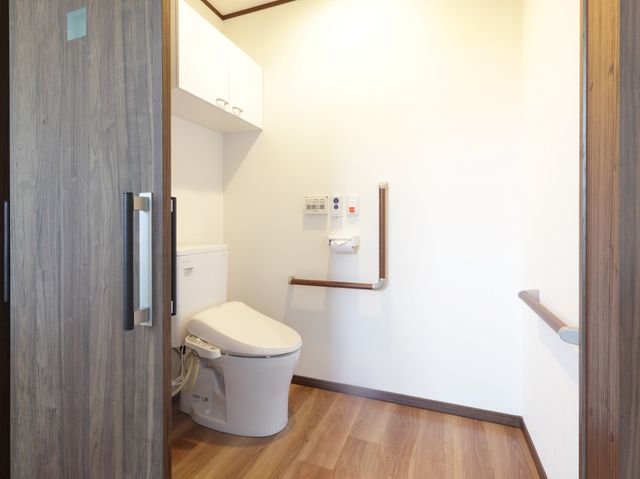 洋風トイレの明るい空間 トイレ 手すりが設置された清潔感あふれるトイレです。利用者の安全と快適さを考えた設計になっています。