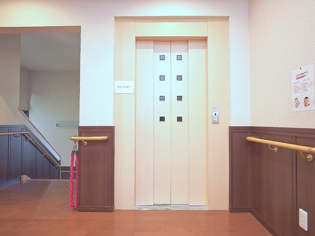 清潔なエレベーターホール エレベーター 手すりが設けられたエレベーター前は、バリアフリーを心掛けた設計です。スタッフと利用者の移動も安全かつ円滑に行えます。