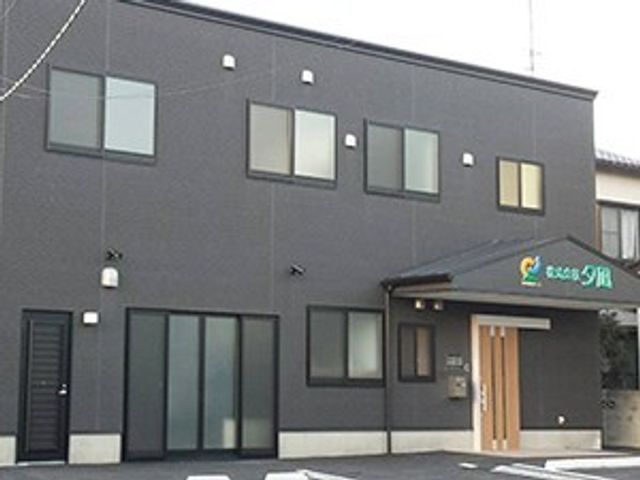 シンプルな外観の施設 外観 外壁がシックな色合いの建物です。入口に明るい看板があり、訪れる方々を温かく迎えています。