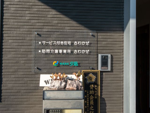 施設正面の看板とインターホン ロゴ 施設の入り口を示す看板と案内があり、訪れる方がすぐに認識できるよう配慮されています。