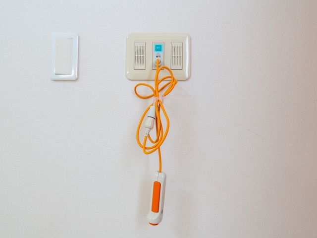 緊急用ブザーの壁面設置 エントランス 壁に設置された緊急用ブザーは安全への配慮を感じさせます。操作しやすい位置にあります。
