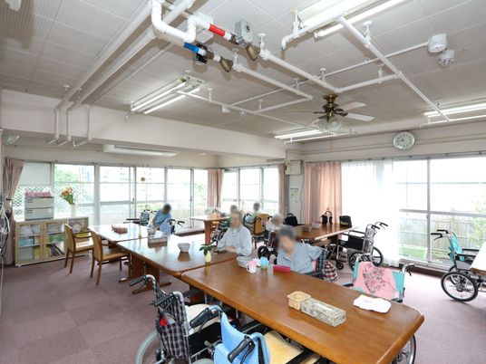 車椅子をご利用の方も着席しやすい、背の高いダイニングテーブルがセッティングされている。入居者様が思い思いの時間を過ごしている。