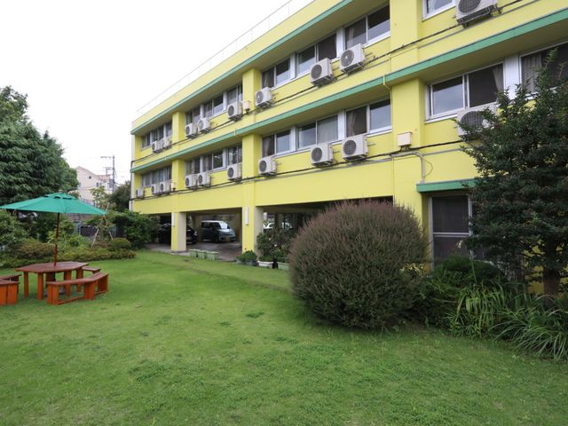 緑豊かな外観風景 外観 緑の草花が心地よい、黄色の建物の外観です。開放的な庭でのひとときを想像してみてください。