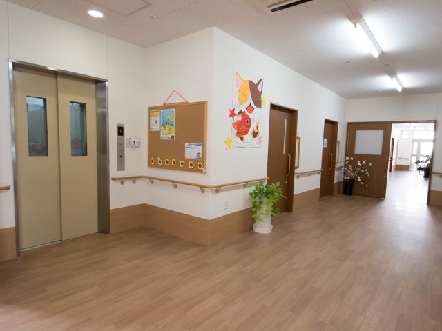 廊下に花と掲示板 廊下 広々とした通路には、明るい装飾と親しみやすい掲示物があり、心温まる雰囲気を提供しています。