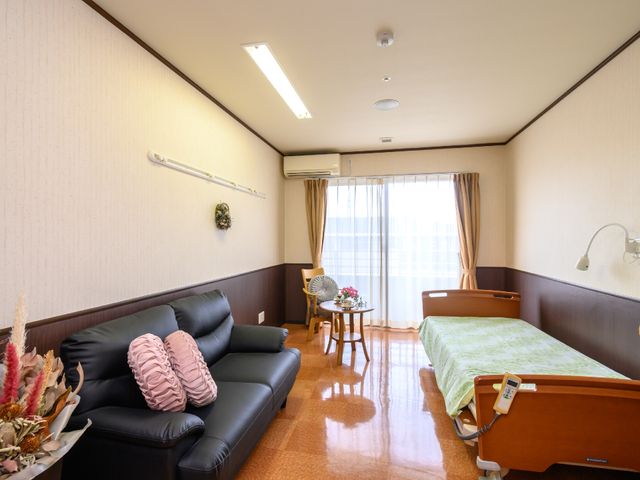 快適な居室の一例 居室 ゆったりとしたソファとベッドが備わり、落ち着いた雰囲気の個室です。大きな窓からは自然光が差し込み、明るく快適な空間を提供しています。