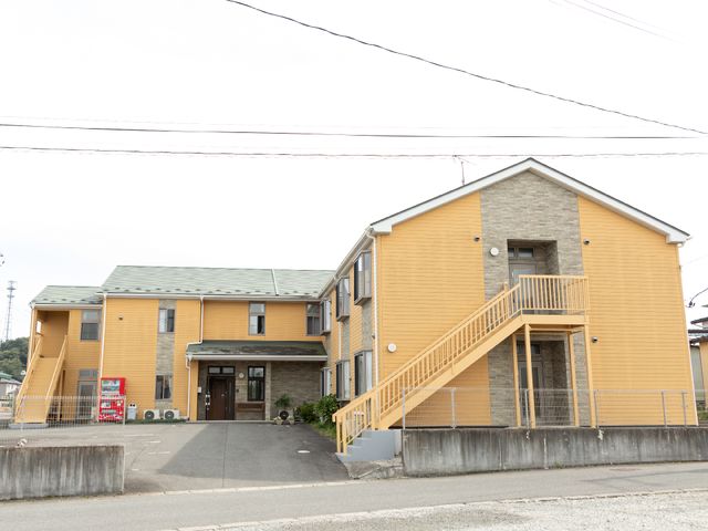 黄色の建物の外観 外観 明るい色合いの建物は、開放感があり、温かみを感じさせるデザインです。入口近くには便利な自動販売機も設置されており、快適に過ごせそうです。