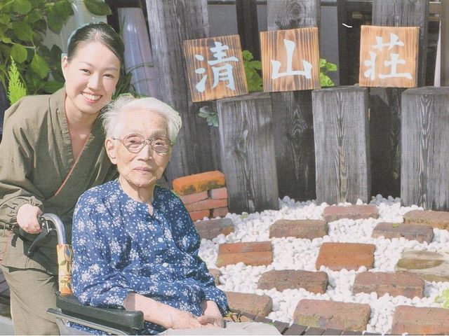 笑顔のスタッフと利用者 日差しの柔らかな中庭で、スタッフが優しく利用者をサポートしています。暖かい雰囲気に包まれた空間で、心地よい時間を過ごせそうです。