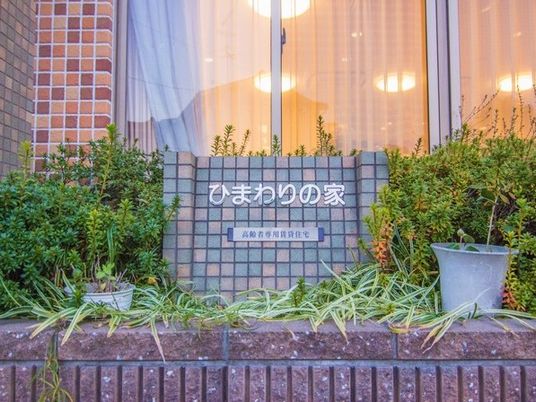 施設名の看板と植栽の外観  