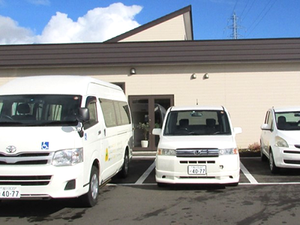 送迎車が並ぶ建物外観  