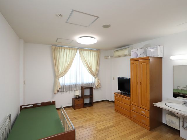 明るい居室の一角 居室 床の木目調と白壁が印象的な居室です。日常生活に必要な家具がそろっており、快適な生活空間を提供しています。