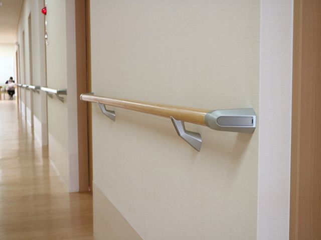 廊下の手すりと床 通路 廊下の手すりは安全に配慮された設計で、歩行のサポートが可能です。奥に見えるやさしい雰囲気の空間が待っています。