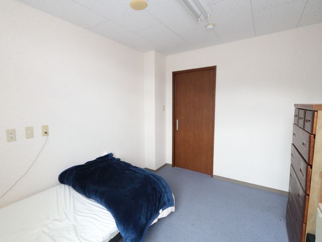シンプルな居室の一角 居室 ゆったりとしたシングルベッドが置かれた落ち着いた雰囲気の個室です。個人のプライバシーを大切にした安らぎの空間が確保されています。