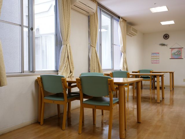 ゆったりした食堂 食堂 窓辺に並ぶテーブルと椅子が設置された、ゆったりと明るい食事スペースです。窓からは自然光が差し込み、穏やかな時間を過ごせるでしょう。