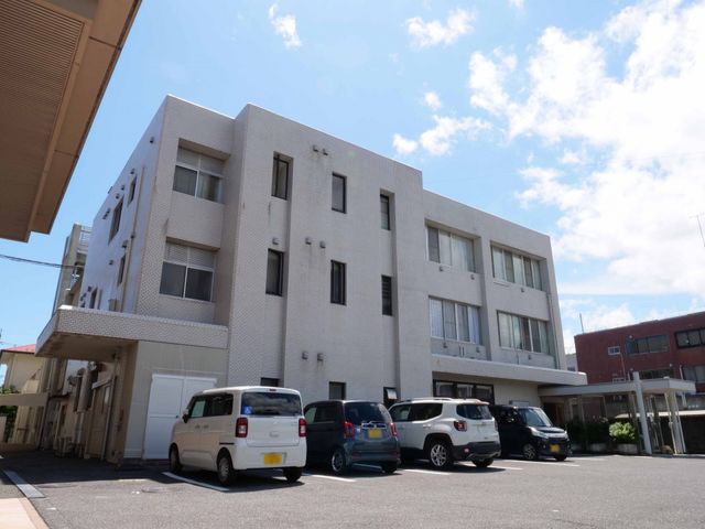 明るい日差しの居室外観 外観 ゆとりある駐車スペースを備えた、白を基調とした清潔感のある建物です。青空の下、穏やかな日常をお過ごしいただける環境がここにあります。