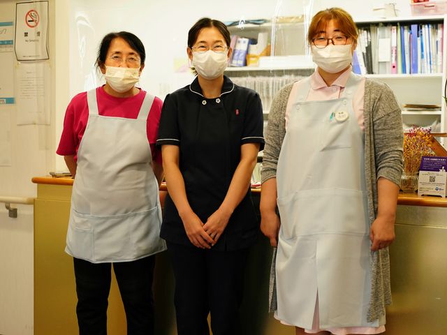 笑顔のスタッフ三人 スタッフ 笑顔で立つスタッフが温かい雰囲気をもたらしており、チームワークの良さが感じられます。働く環境として心地良い印象を受けます。