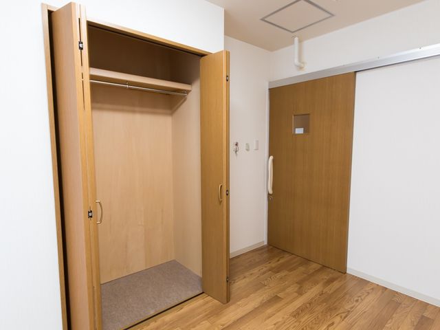 洋室のクローゼットと扉 収納 ゆとりを感じる居室の一角です。洋服や荷物を収納できる広めのクローゼットが完備されており、快適な生活空間が確保されています。