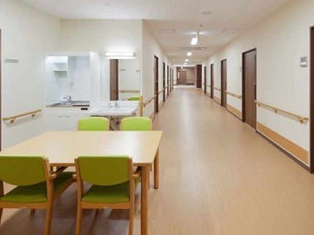 清潔感のある廊下 共有スペース 清潔で広々とした通路には手すりが整備され、安心して歩行できる環境が整っています。休憩に適したテーブルセットも用意され、機能性と快適さを兼ね備えています。