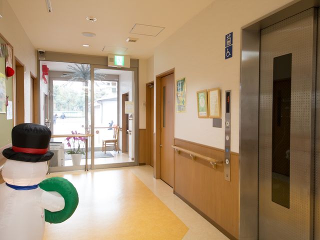 明るい廊下とエレベーター 玄関 手すり付きの廊下は、移動の安全を支えます。エレベーター近くには座れるスペースもあり、快適な環境が整っています。