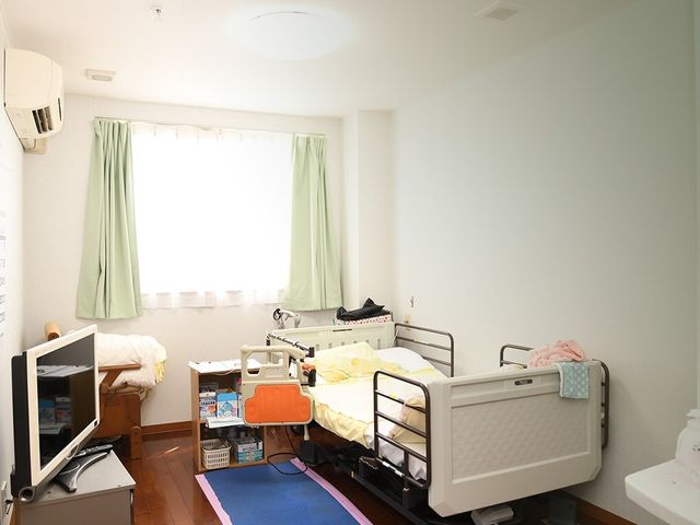 明るい居室のベッドと家具 居室 快適そうなベッドが整えられた個室です。個人の必需品を置くための収納スペースも確保されております。