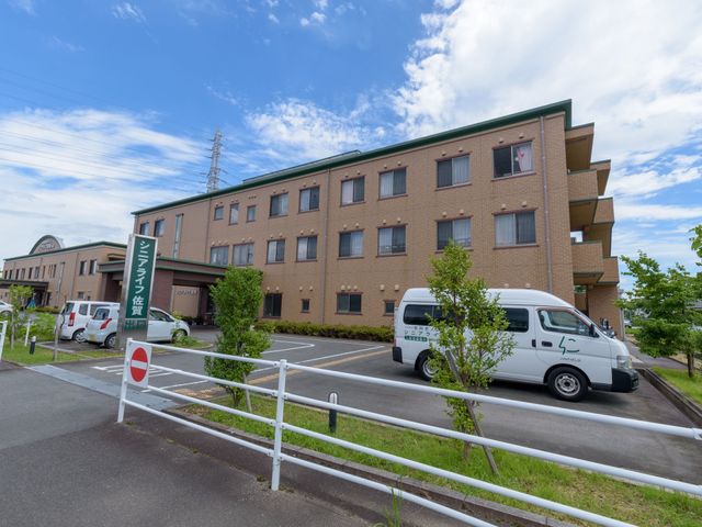 施設の風景と送迎車 外観 緑に囲まれた落ち着いた雰囲気の建物外観です。清潔感のある施設が、訪れる方々を温かく迎え入れます。