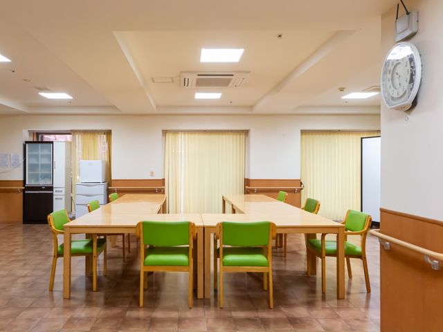 木のテーブルと椅子のある部屋 ダイニングルーム   自然光が入る明るい空間で、快適に食事の時間を過ごせます。車椅子でのアクセスも安心です。