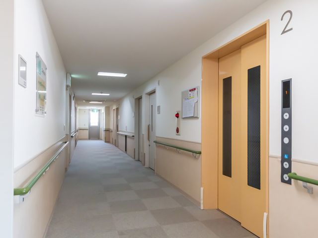 明るい長い廊下 廊下 自然光が差し込む長い廊下が続いています。壁には手すりが設置され、安心して歩行できます。