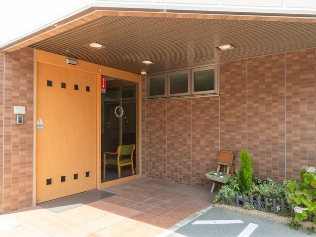 温かい雰囲気の入口 エントランス 緑の椅子が置かれたエントランスは、温かみがあり訪れる人を優しく迎えます。