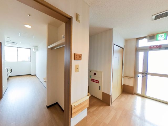 明るい廊下と部屋 ケア 広々とした廊下が確保されており、どなたでもゆったりと移動できる環境が整っています。窓からは自然光が差し込み、温かな雰囲気をもたらしています。