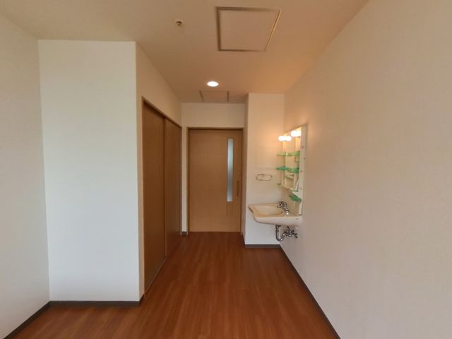 清潔な洗面台付き廊下 居室 手入れが行き届いた明るい廊下は、洗面台が備わっており利便性を提供しています。安心して働ける環境が整っています。