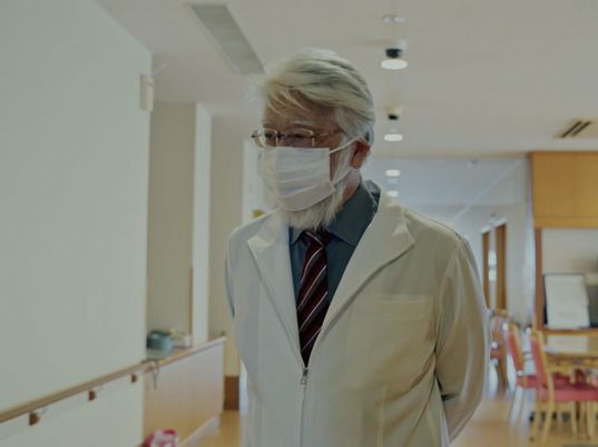 白衣姿の男性と明るい廊下