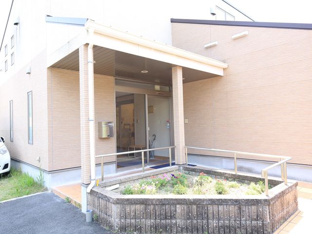 居心地の良いエントランス 外観 入口はバリアフリー設計で、花々が彩る心安らぐ空間となっており、訪れる人を暖かく迎えます。