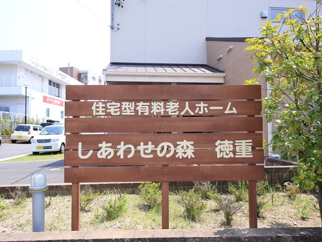 看板と緑の風景 外観 あたたかな陽光に照らされた看板が迎えてくれる、明るい雰囲気の職場です。