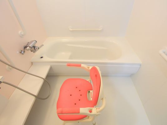 白を基調とした、清潔感のある浴室である。洗い場には背もたれ付きの椅子が１脚置かれており、壁には複数の手すりがある。
