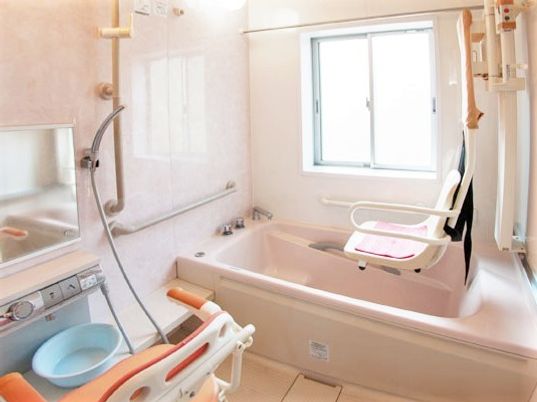 一人用の浴槽が設置された浴室。シャワーやリフトもあり、手すりが壁についている。