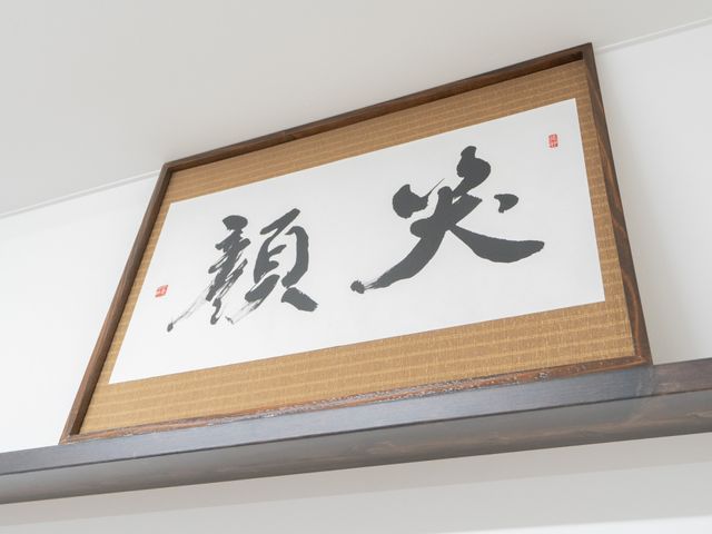 壁の掛け物 掲示物 壁に飾られた掛け軸は、心を落ち着かせるシンプルなデザインです。施設内の雰囲気を引き締めています。