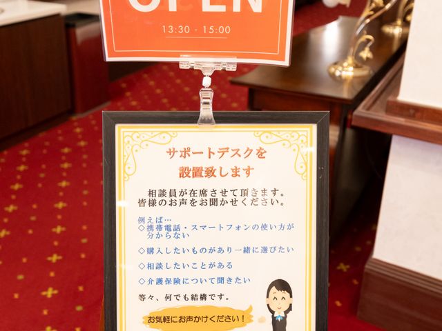 看板の前に飾られた赤絨毯 看板 「いらっしゃいませ」と書かれた案内が入り口を暖かく迎えています。親切なサポートデスクも完備されています。